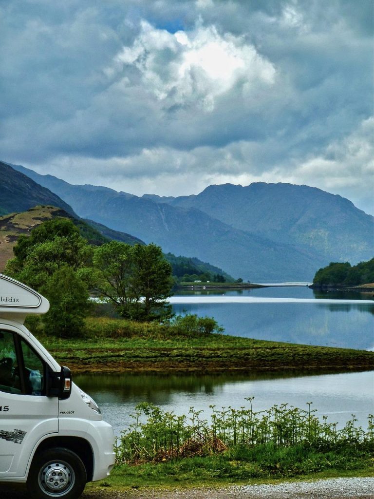 Camper op een schilderachtige bergweg in Noorwegen met fjord- en berglandschap op de achtergrond
